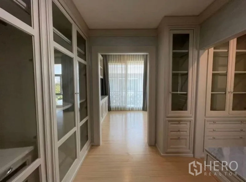 Townhouse for sale - Hallway lined with glass cabinetry leading to a windowed room and balcony.