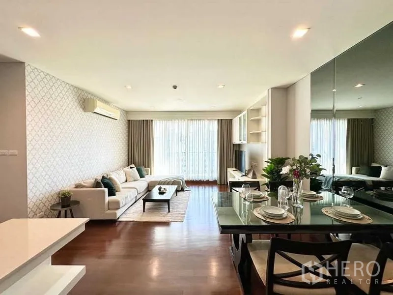 Condominium for rent in Watthana, Bangkok - Wide living–dining space with floor-to-ceiling curtains and a patterned feature wall.