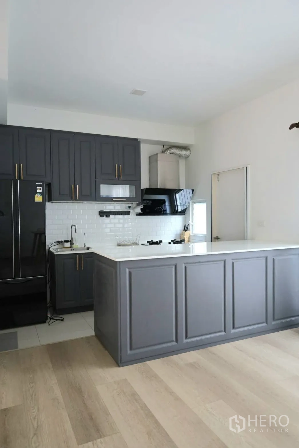 联排别墅 for rent in Prawet, Bangkok - 现代厨房，灰色柜体、白色岛台与地铁砖背景墙。
