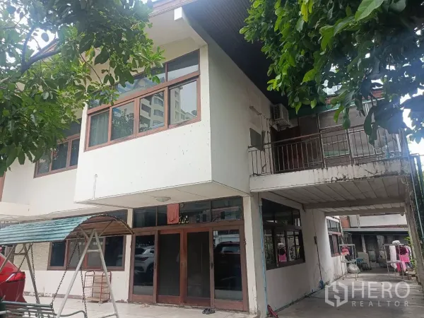 独立式住宅 出租在Bang Rak, Bangkok - 房屋立面特写，大片窗户与小阳台，树荫遮蔽。