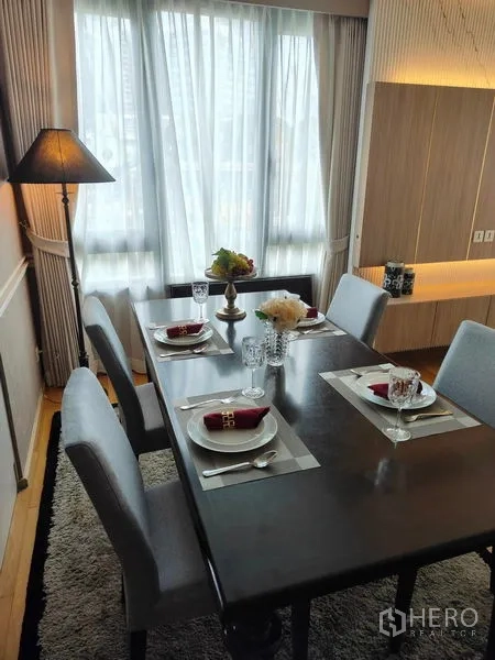 公寓 出租或出售在Pathum Wan, Bangkok - 餐区摆放四人餐桌餐具，地毯与落地灯，临近大窗。