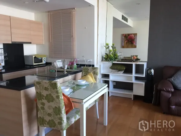 公寓 出租在Watthana, Bangkok - 开放式厨房，黑色石材中岛，玻璃餐桌与浅木色橱柜。