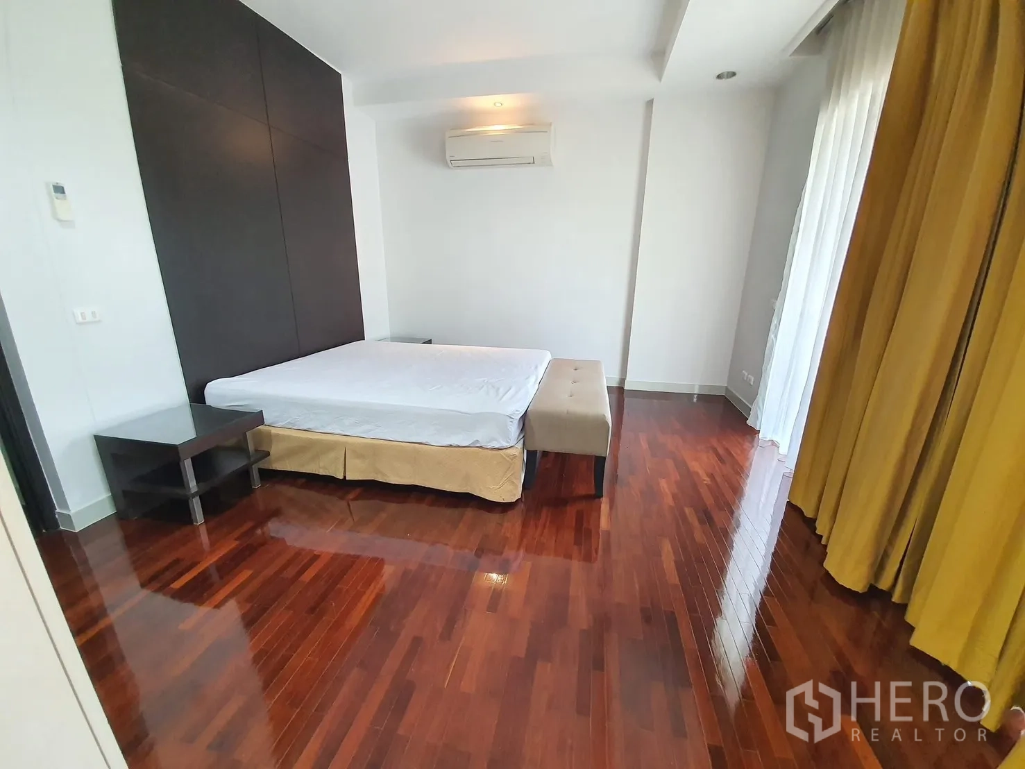 Detached House for rent in Wang Thonglang, Bangkok - Spacious master bedroom with double bed, glossy wood floors, large windows, and AC unit.