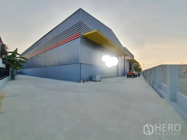 Warehouse for rent in Sai Mai, Bangkok - Modern steel warehouse exterior with roller shutters and a wide concrete driveway in Sai Mai, Bangkok.