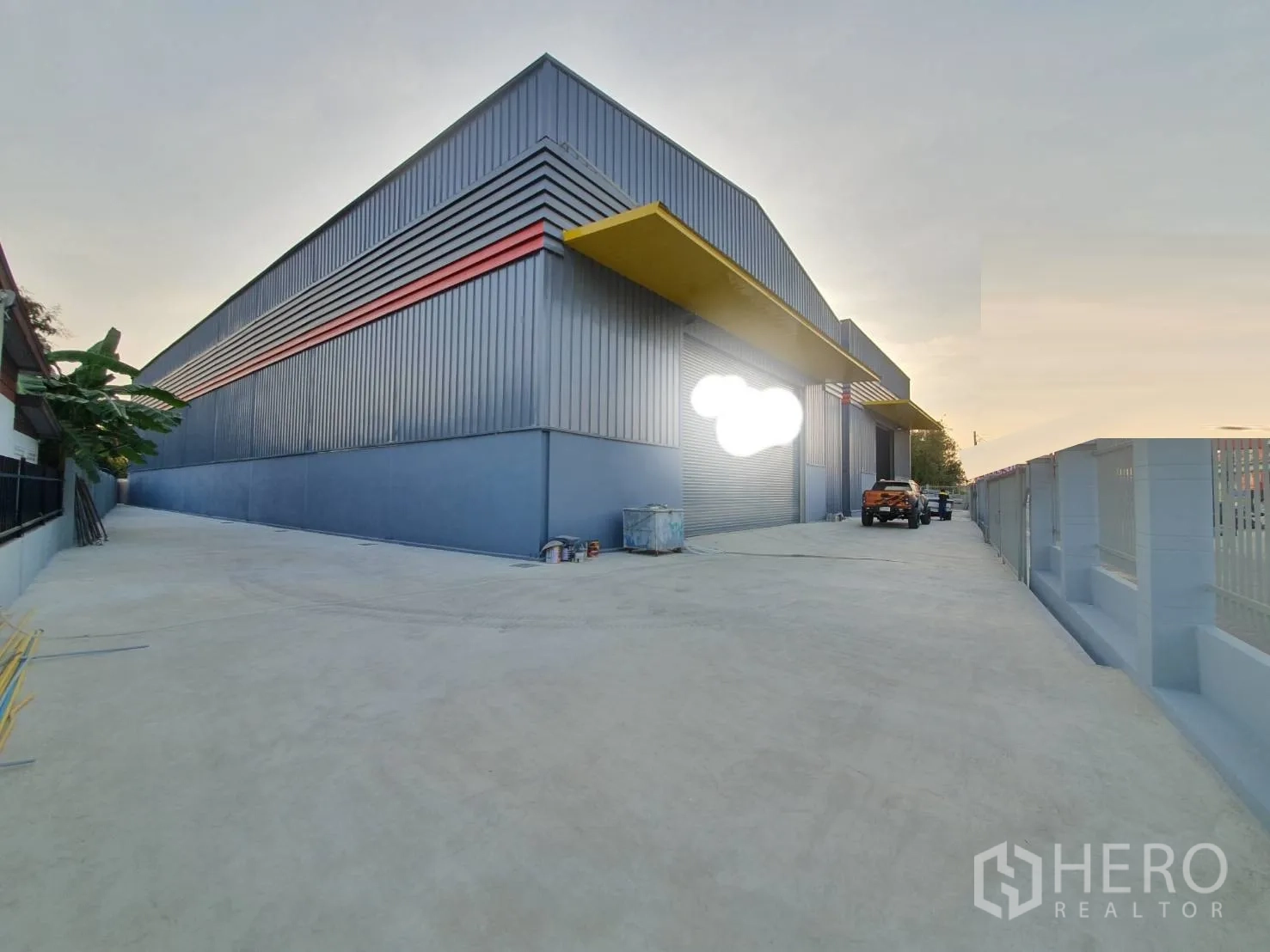 Warehouse for rent in Sai Mai, Bangkok - Modern steel warehouse exterior with roller shutters and a wide concrete driveway in Sai Mai, Bangkok.