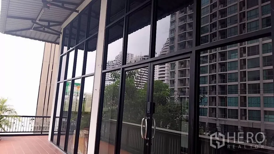 零售空间 出租 - 临街落地玻璃门面与露台，可见周边公寓景观。