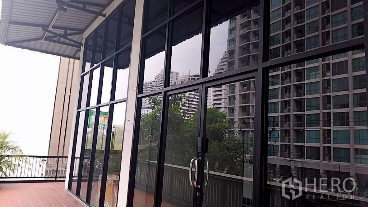 零售空间 出租 - 临街落地玻璃门面与露台，可见周边公寓景观。