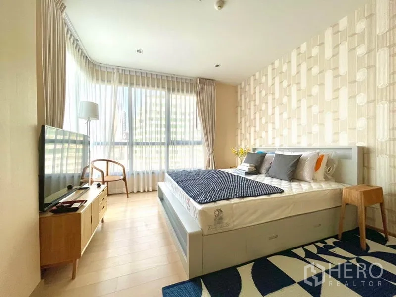 Condominium for rent or sale in Watthana, Bangkok - Master bedroom with king bed, accent wall and wide windows bringing natural light.
