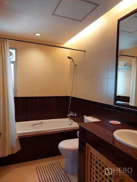 Apartment for rent - Tiled bathroom with bathtub, shower over tub, vanity and large mirror.