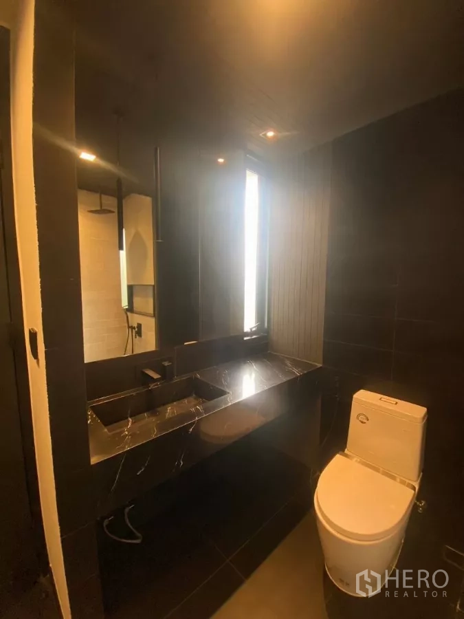 Townhouse for rent in Huai Khwang, Bangkok - Guest bathroom with a black marble vanity and modern toilet.