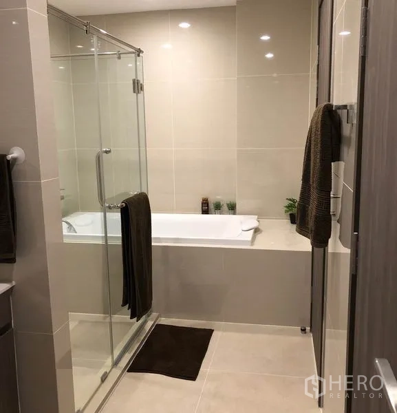 Condominium for rent in Bang Na, Bangkok - Modern bathroom with a glass shower enclosure and a full bathtub.