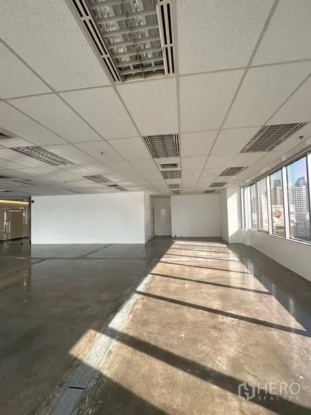Office Space for rent in Pathum Wan, Bangkok - Bright open‑plan office with large windows, polished concrete floor, and grid ceiling overlooking Bangkok skyline.