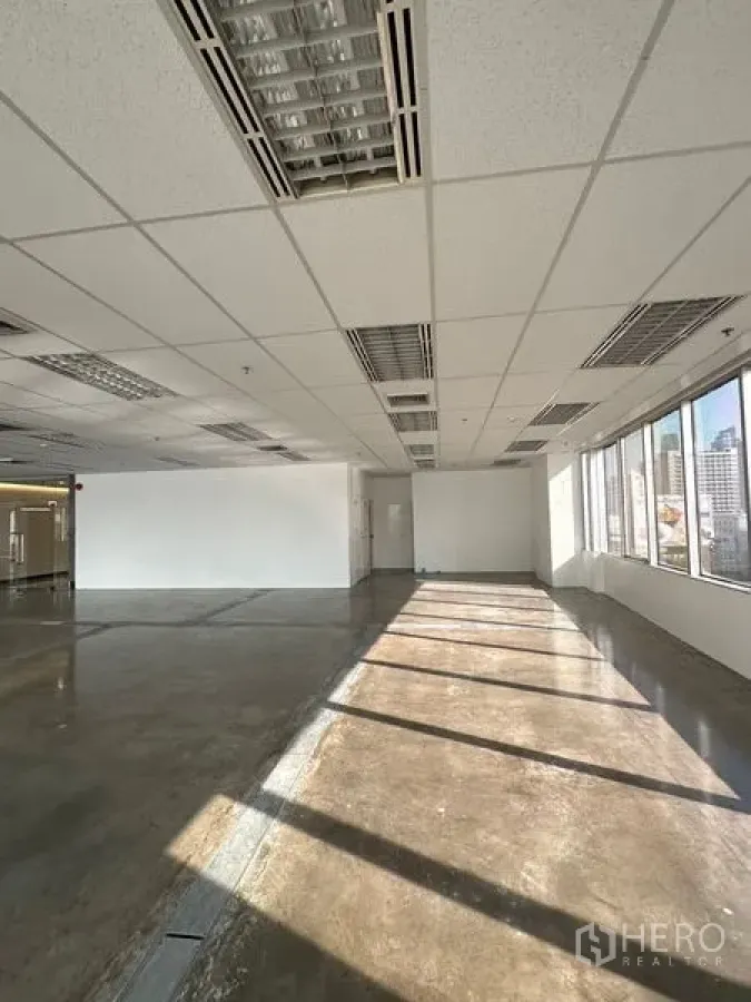 Office Space for rent in Pathum Wan, Bangkok - Bright open‑plan office with large windows, polished concrete floor, and grid ceiling overlooking Bangkok skyline.