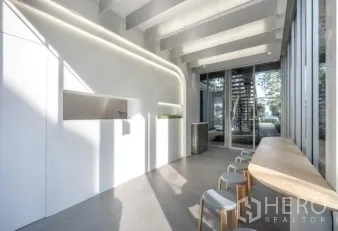 Retail Space for rent in Khlong Toei, Bangkok - Minimal white retail space with curved LED lighting, high exposed beams, and a glass entrance.