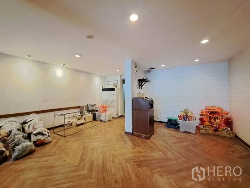 Shophouse for rent in Watthana, Bangkok - Open room with wood flooring, white brick walls and recessed lighting.