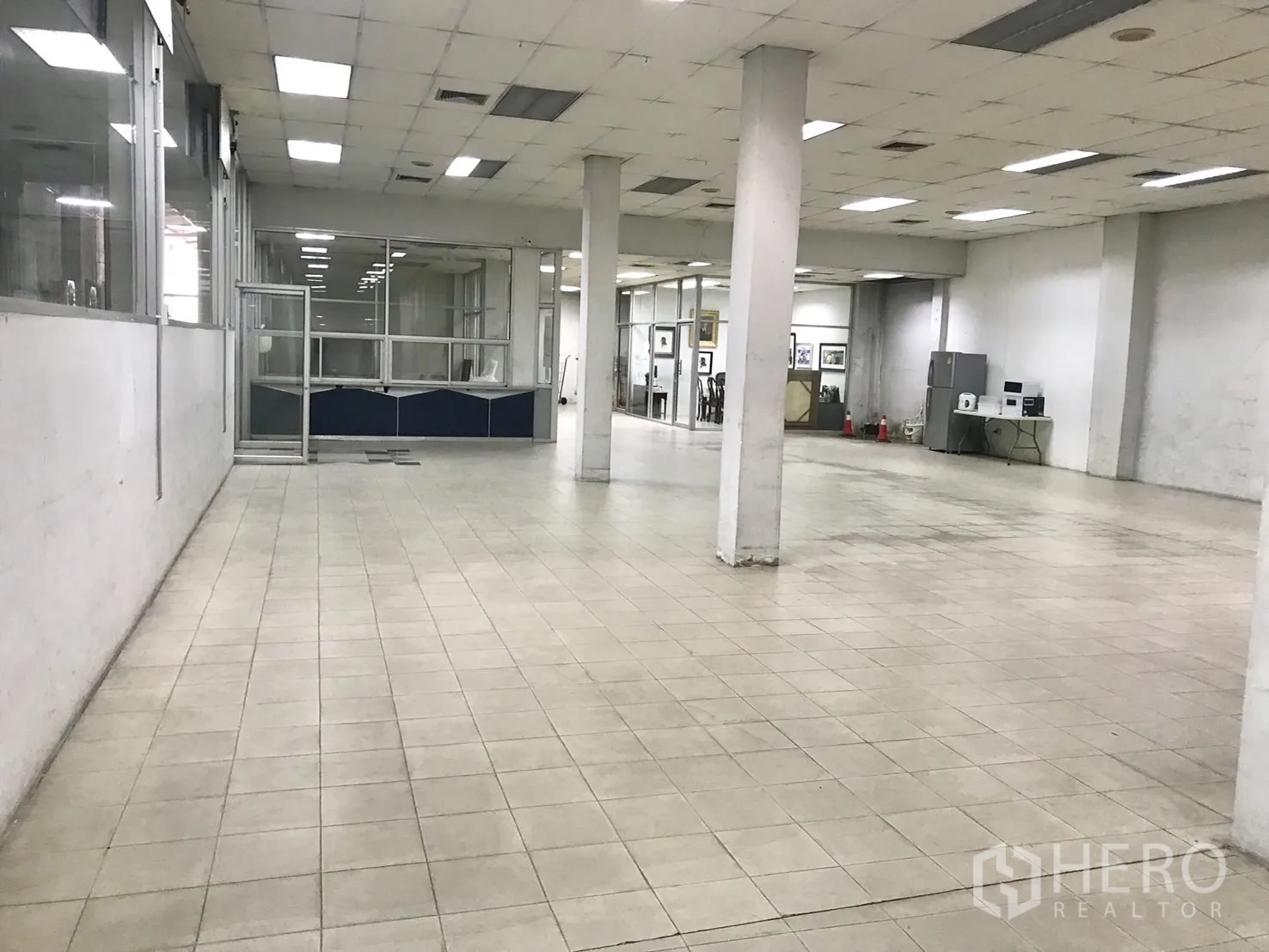 โกดัง for rent in Phra Khanong, Bangkok - พื้นที่ภายในปูพื้นกระเบื้องขนาดใหญ่ มีเสา โคมไฟเพดาน และห้องกระจกกั้นสำนักงาน