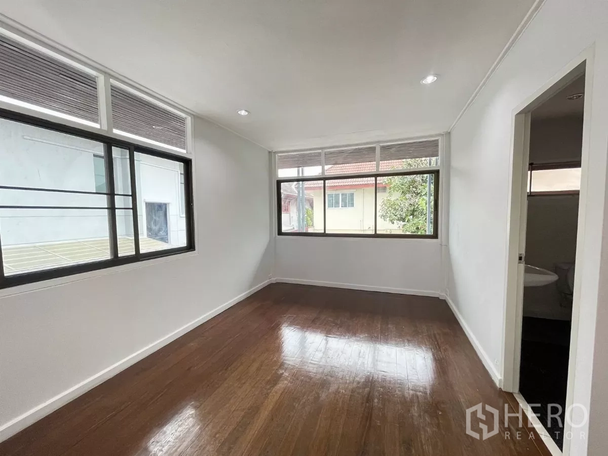 Home Office for rent in Din Daeng, Bangkok - Bright bedroom with polished wooden floor, wide windows and an ensuite door.