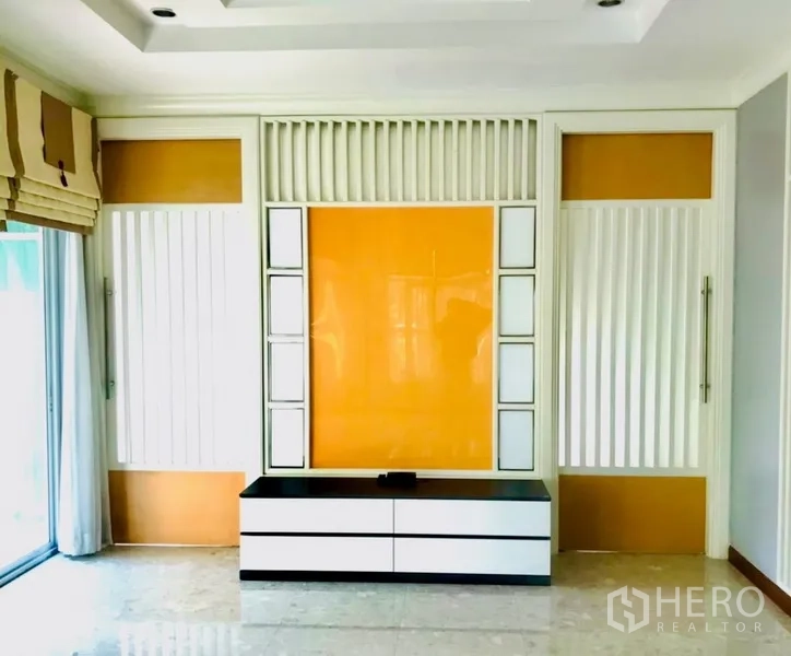 บ้าน ให้เช่าหรือขายในBang Na, Bangkok - ผนังฟีเจอร์พร้อมชั้นวางทีวีในห้องนั่งเล่นสมัยใหม่