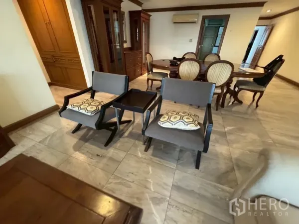 Condominium for rent in Watthana, Bangkok - Open-plan lounge and dining area with marble floors, wooden cabinetry, and upholstered chairs.
