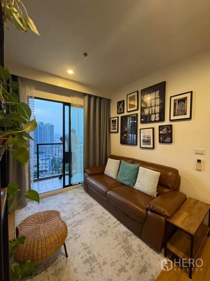 คอนโด ให้เช่าในWatthana, Bangkok - มุมนั่งเล่นติดผนังแกลเลอรี ม่านทึบ และบานเลื่อนออกสู่ระเบียงเห็นวิวสกายไลน์