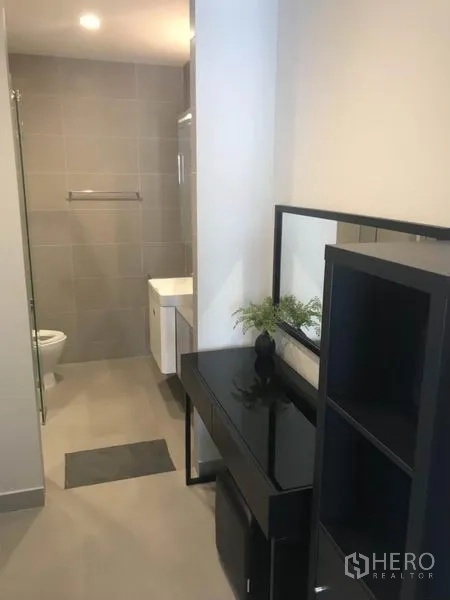 公寓 出租或出售在Pathum Wan, Bangkok - 走廊通向灰色瓷砖浴室，带洗手台和玻璃淋浴间