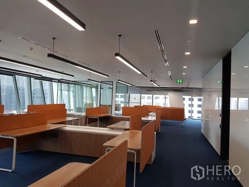 สำนักงาน ให้เช่าในHuai Khwang, Bangkok - พื้นที่สำนักงานแบบโอเพ่นแพลน โต๊ะทำงานยาว ฉากกั้นสีส้ม ผนังกระจก และวิวเมืองผ่านหน้าต่างบานใหญ่