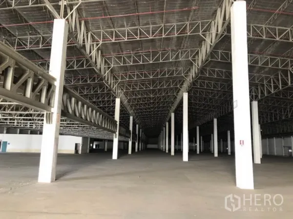 货栈 出租在Lam Luk Ka, Pathum Thani - 仓库内部高挑空间，钢桁架屋顶与成排立柱。
