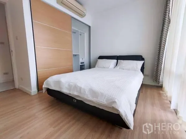 Condominium for rent in Watthana, Bangkok - Second bedroom with large wardrobe, air-conditioner and sheer curtains over tall windows.