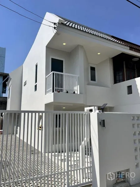 Townhouse for sale in Phra Khanong, Bangkok - Fresh white townhouse exterior with gated entry and small balcony in Phra Khanong.