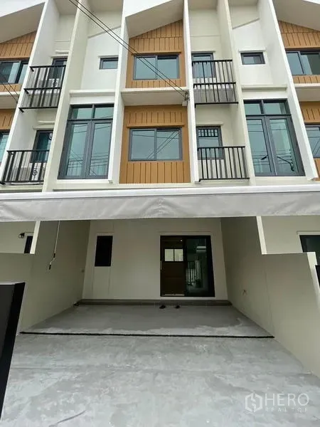 Townhouse for rent in Prawet, Bangkok - Front view of the townhouse facade showing covered carport and balconies.
