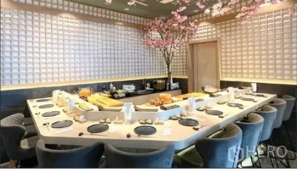 Retail Space for rent - U-shaped sushi counter with multiple seats in a modern Japanese-style dining room, grid-pattern walls and cherry blossom decor.