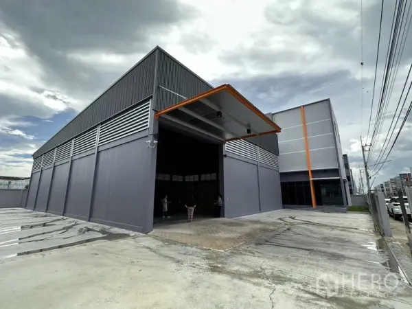 Factory for rent or sale in Lam Luk Ka, Pathum Thani - Covered loading bay with tall roller shutter door at a contemporary factory exterior.