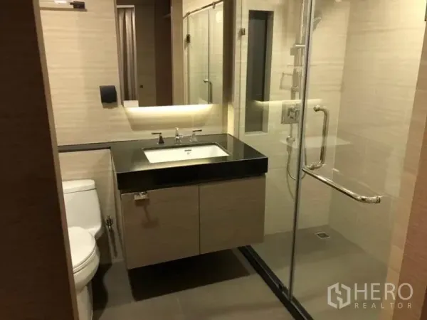 公寓 出租在Pathum Wan, Bangkok - 现代卫浴，玻璃干湿分离、黑色台面盥洗台与坐厕。