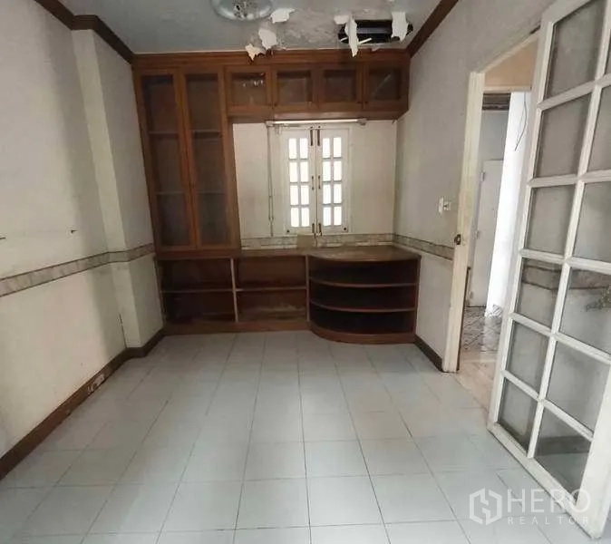 独立式住宅 出售在Phra Khanong, Bangkok - 小巧房间配木质柜体与瓷砖地面，可作茶水间或家庭办公室。