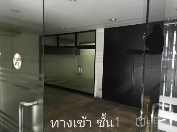 带办公室的家 出租在Khlong Toei, Bangkok - 一层入口，玻璃门与黑色特色墙的居家办公楼。