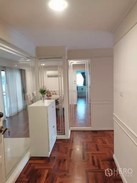 Apartment for rent in Watthana, Bangkok - Entrance hallway with mirrored glass partitions and a view toward the dining area and bedroom.
