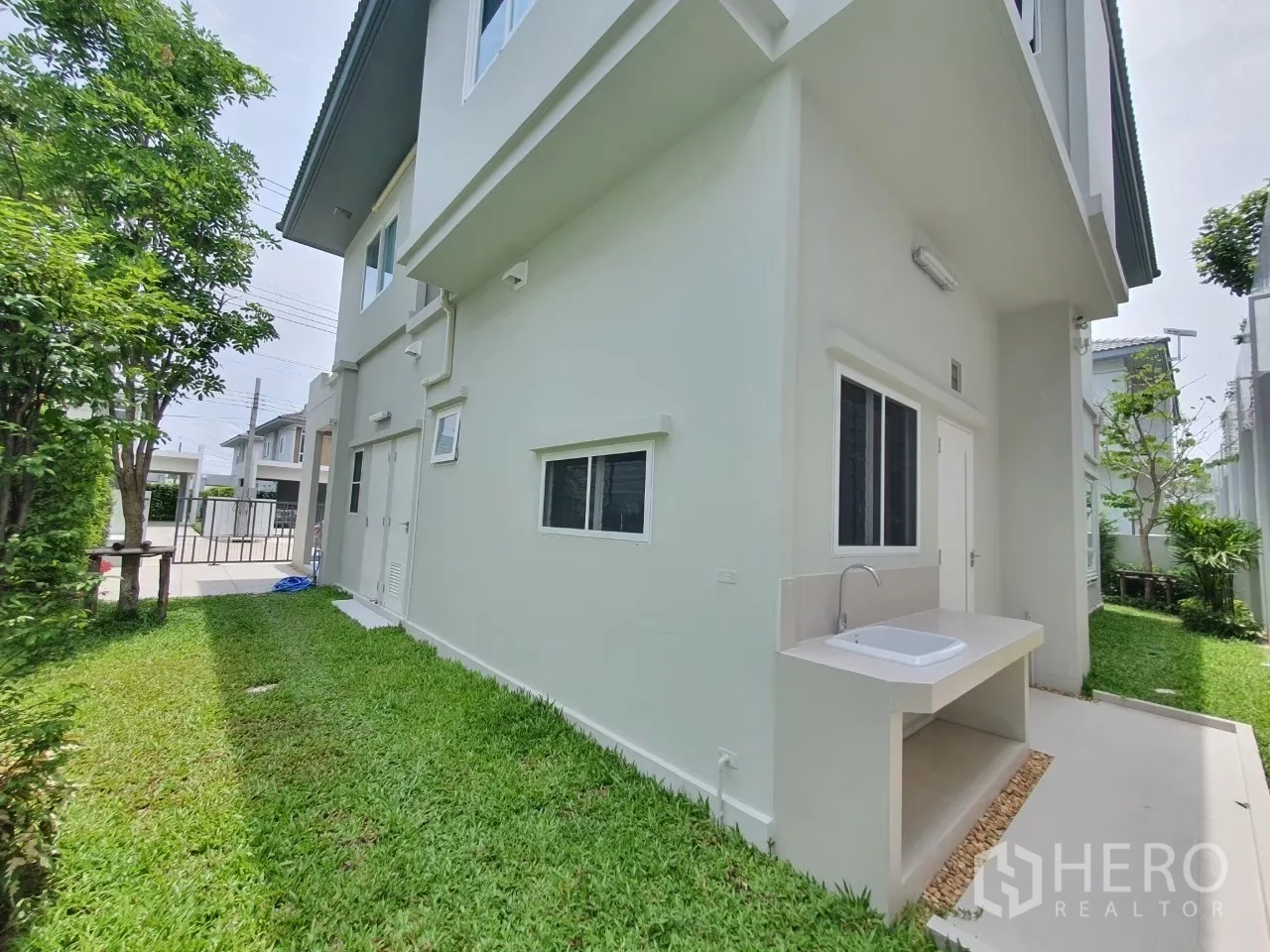 独立式住宅 出租在Prawet, Bangkok - 侧院草坪，带室外操作水槽与服务门。