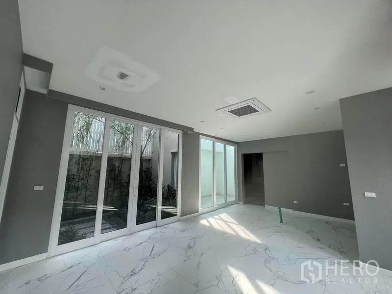 Detached House for sale in Yan Nawa, Bangkok - Bright family area with floor-to-ceiling sliding glass doors opening to a private courtyard.
