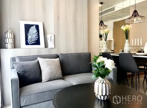 คอนโด ให้เช่าในWatthana, Bangkok - ห้องนั่งเล่นร่วมสมัย โซฟาสีเทา แจกันดอกไม้ ผนังกระจกเงา และส่วนทานอาหารพร้อมโคมแขวน