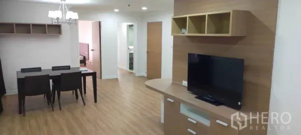 公寓 出租在Watthana, Bangkok - 开放式客厅与餐区，木地板、电视柜和四人餐桌。