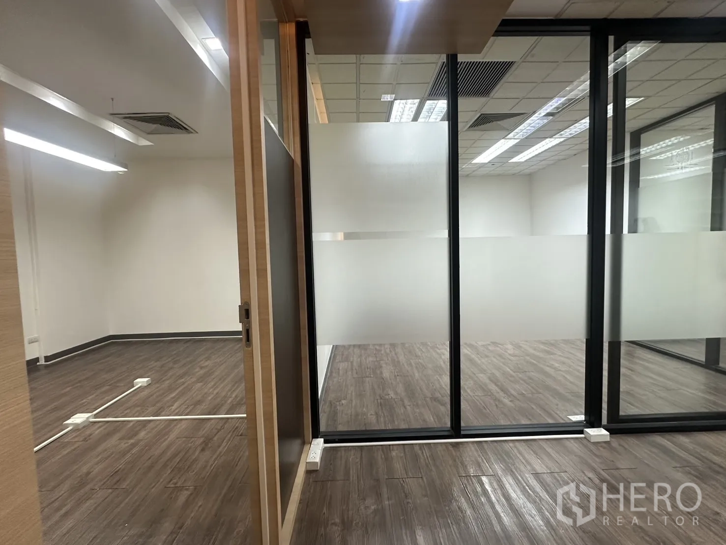 办公室 for rent in Pathum Wan, Bangkok - 滑动门通向带磨砂玻璃隔断的办公室，深色木纹地板。