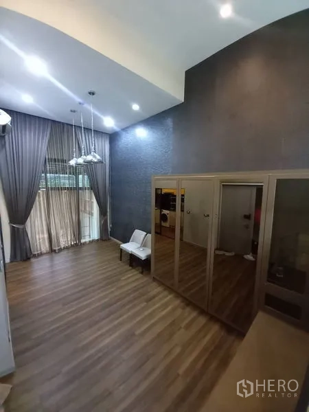 Townhouse for rent in Suan Luang, Bangkok - Double-height multipurpose room with pendant chandelier, floor-to-ceiling curtains and mirrored wardrobe.