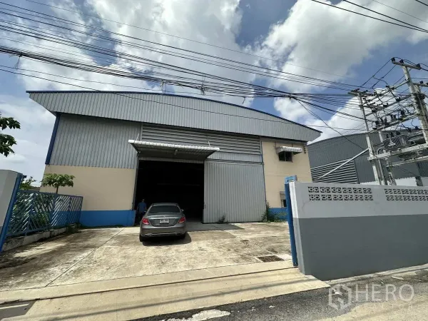 โรงงาน ให้เช่าในPathum Thani - ด้านหน้าโรงงานพร้อมประตูบานเลื่อนขนาดใหญ่และทางเข้า–ออกคอนกรีต ที่ลาดหลุมแก้ว ปทุมธานี