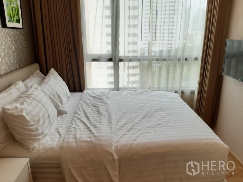 公寓 出租在Watthana, Bangkok - 采光良好的卧室，设大窗、城市景观与白色床品的双人床。