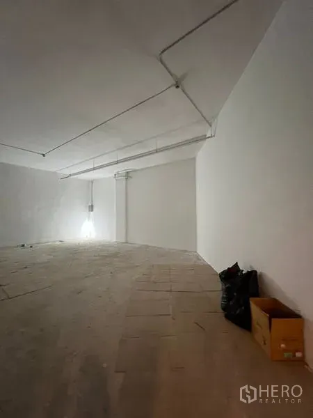 Retail Space for rent - Corner view of the retail unit showing smooth white walls, ceiling conduits and a raised floor section.