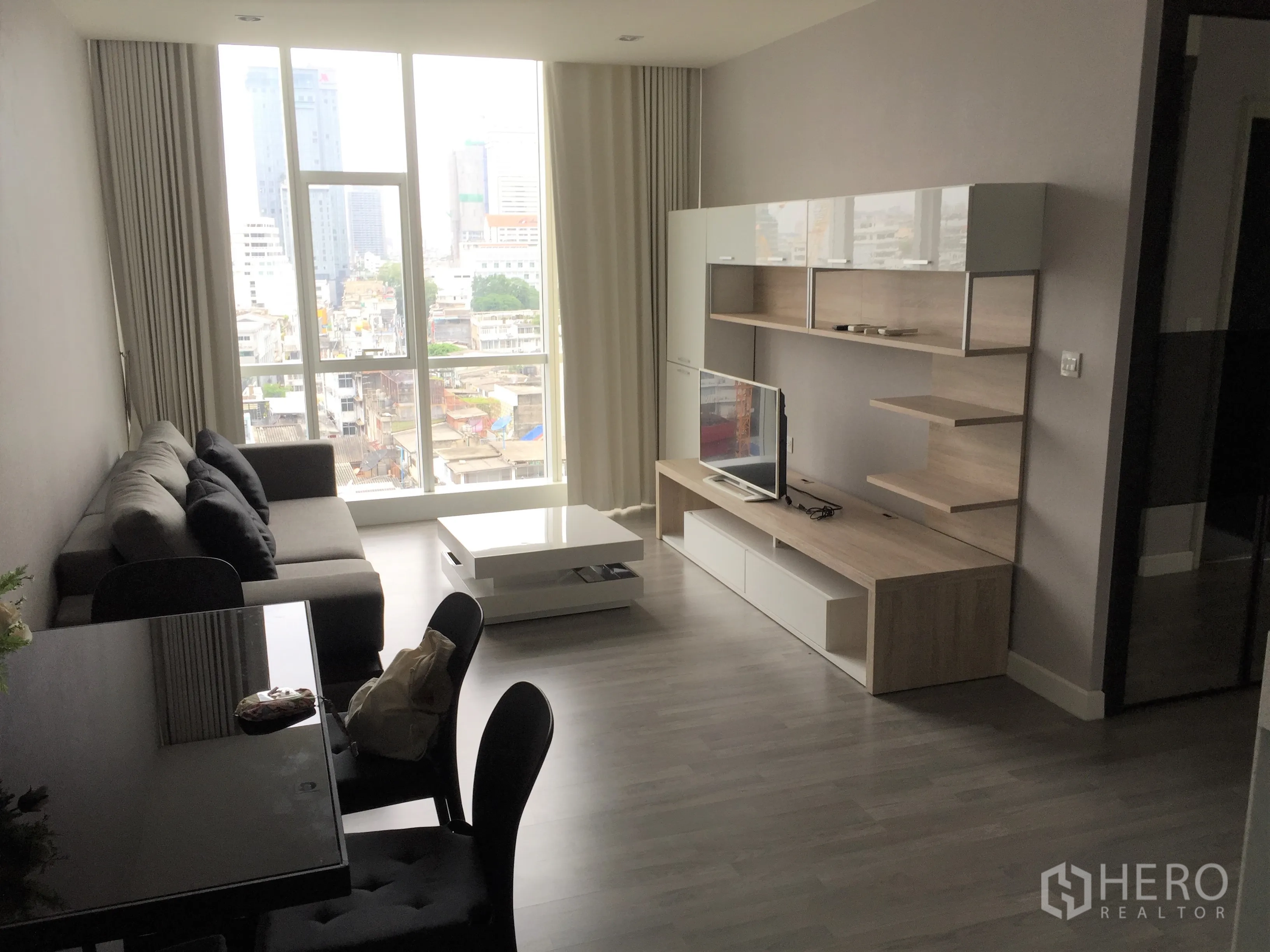 Condominium for rent in Bang Rak, Bangkok - Living room with floor-to-ceiling windows, skyline view, and built-in TV cabinet in Bang Rak, Bangkok.