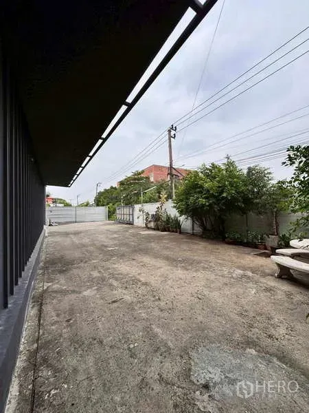 Warehouse for rent in Prawet, Bangkok - Wide concrete yard and gate providing truck access beside the warehouse.