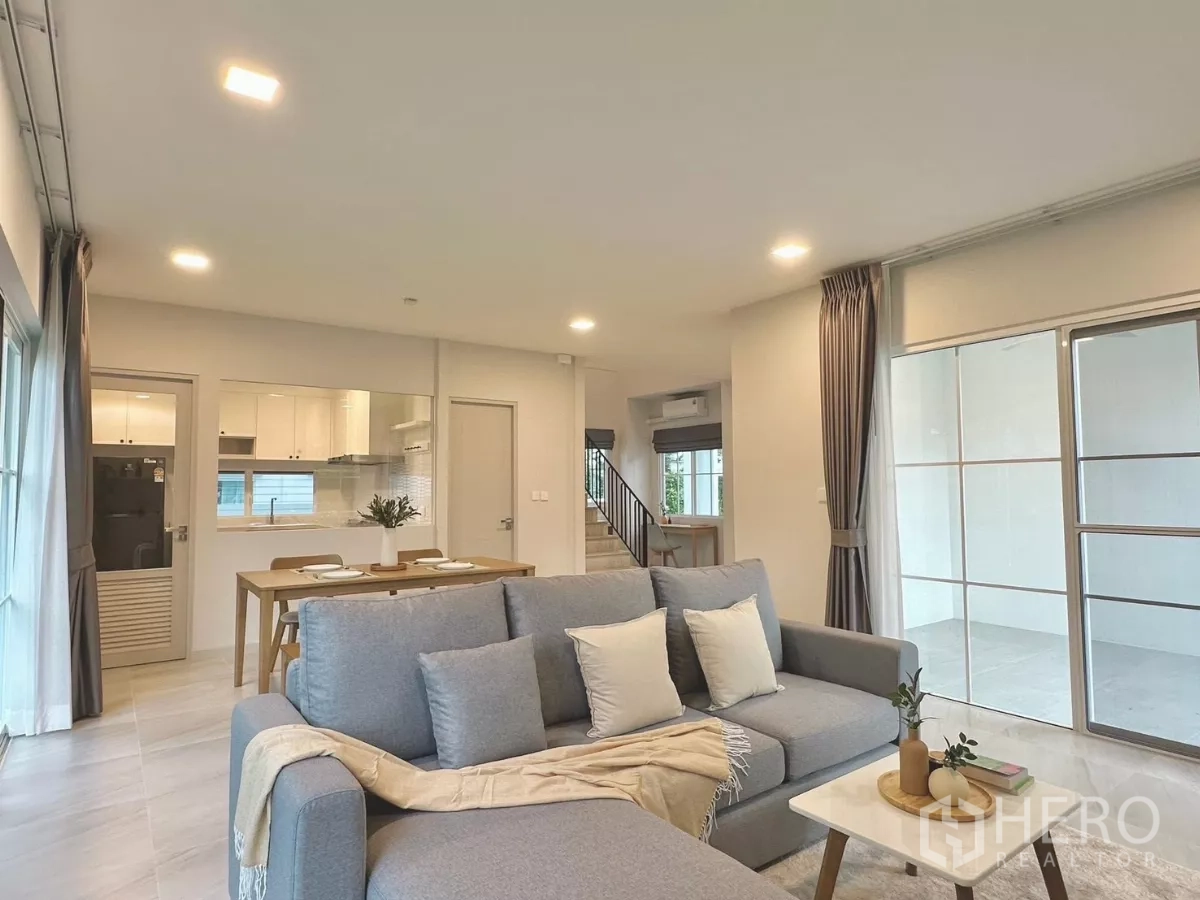 Detached House for rent in Bang Phli, Samut Prakan - Open-plan layout showing sofa, dining set, kitchen pass-through and covered patio.