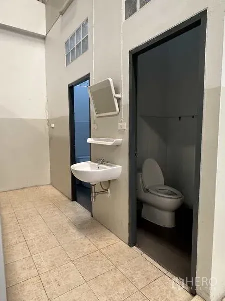 Factory for rent in Samut Prakan - Clean staff restrooms with separate toilet cubicles and a wall-mounted sink.