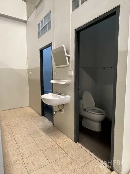 Factory for rent in Samut Prakan - Clean staff restrooms with separate toilet cubicles and a wall-mounted sink.